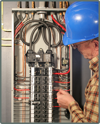 A person in a blue hard hat and plaid shirt inspects a complex electrical breaker panel with labeled wires. The scene conveys focus and technical expertise.