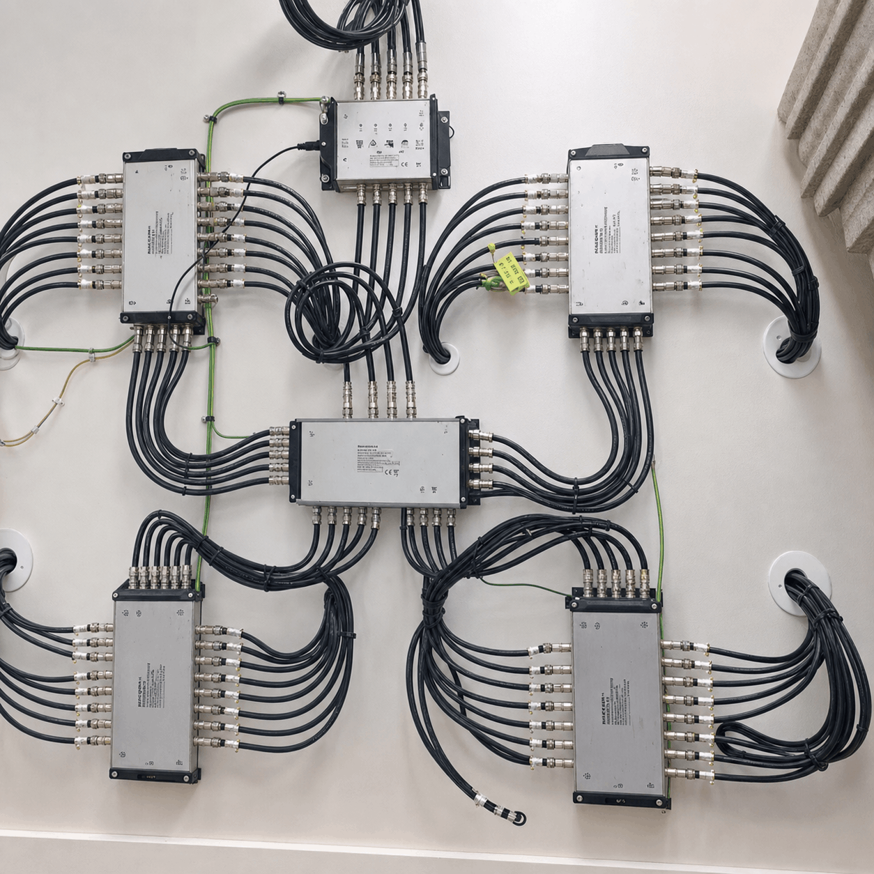 A network of cables connected to several metal distribution boxes arranged in a symmetrical pattern on a wall. The setup conveys order and precision.
